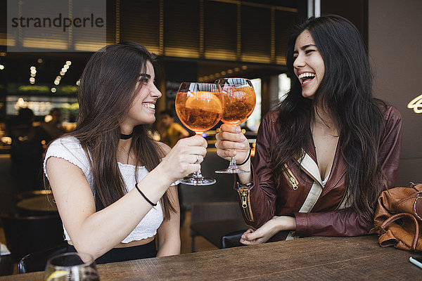 Zwei glückliche junge Frauen stoßen in einer Bar an.
