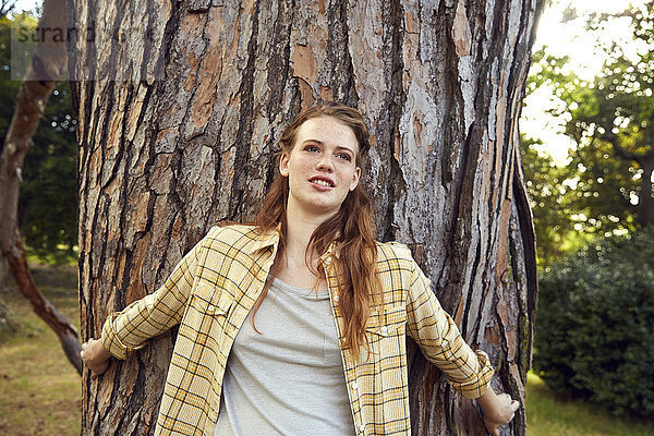 Bildnis einer jungen Frau  die sich an den Baumstamm lehnt