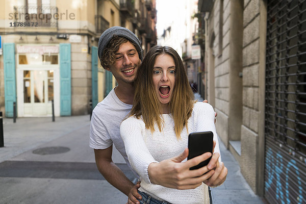 Ein glückliches junges Paar  das die Stadt mit einem Selfie betritt.