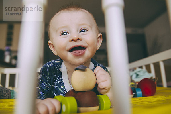 Porträt eines glücklichen Jungen mit Holzspielzeug in der Krippe