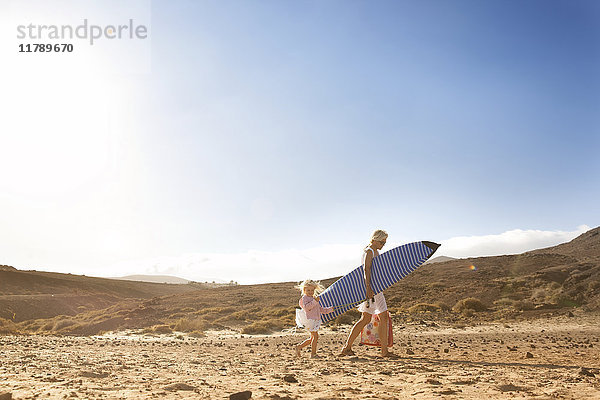 Spanien  Fuerteventura  Mutter und Tochter laufen mit Surfbrett am Strand