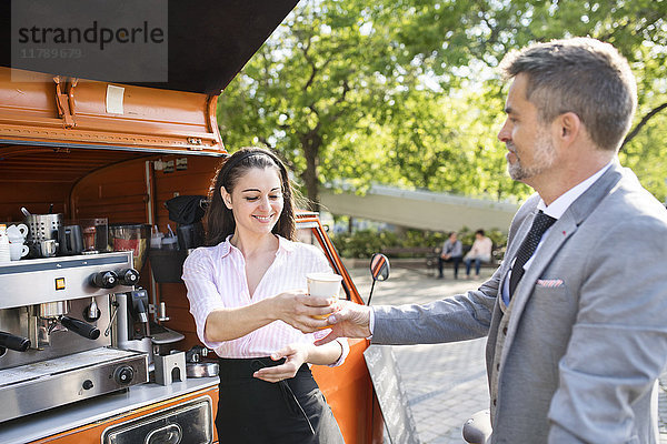 Geschäftsmann  der Kaffee zum Mitnehmen auf der Straße kauft.