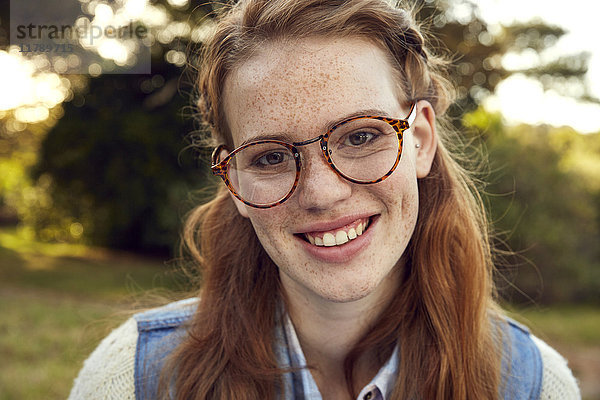 Porträt der rothaarigen jungen Frau mit Sommersprossen und Brille