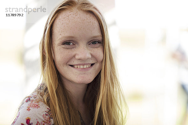 Porträt eines lächelnden Mädchens mit langen roten Haaren