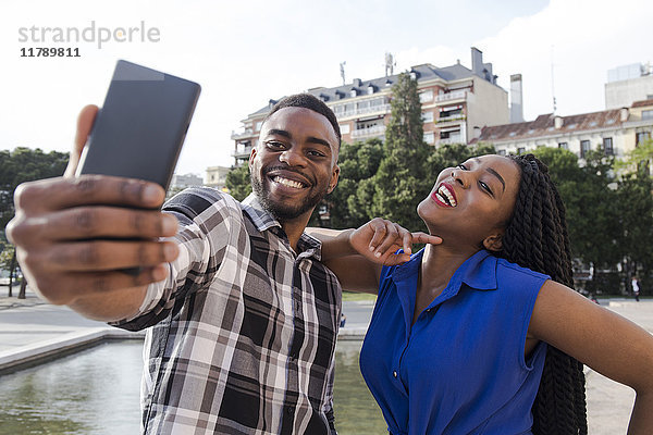 Porträt eines glücklichen jungen Paares  das sich selbst mit dem Handy fotografiert.