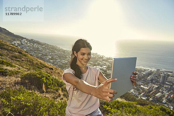 Südafrika  Kapstadt  Signal Hill  junge Frau über der Stadt mit einem Selfie mit Tablette