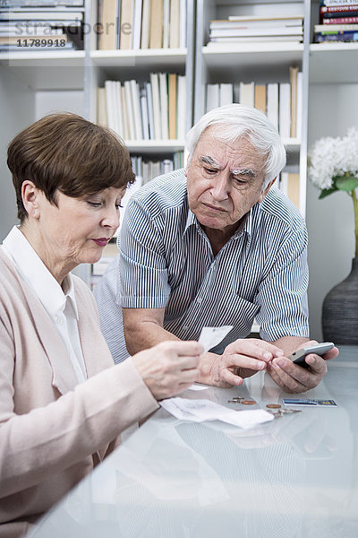 Seniorenpaar mit Rechnungen und Taschenrechner zur Kontrolle der Ausgaben