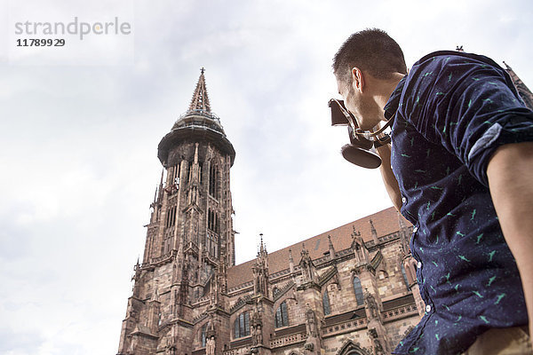 Deutschland  Freiburg  junger Mann beim Fotografieren des Klosters