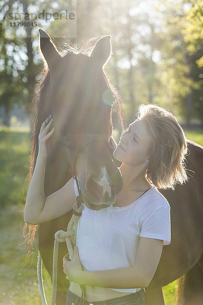 Junge Frau mit Pferd im Gegenlicht
