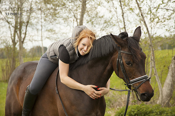 Lächelnde junge Frau auf einem Pferd