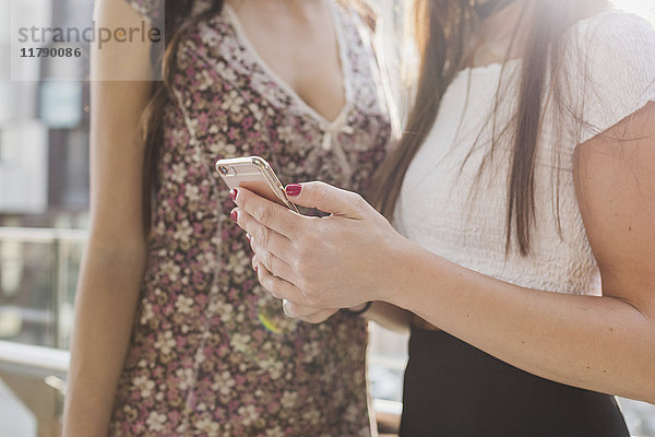 Zwei junge Frauen teilen sich das Handy in der Stadt.