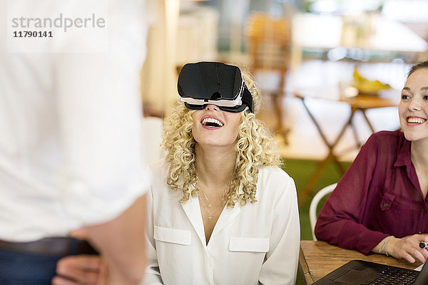 Blonde Frau beim Ausprobieren der VR-Brille in einer Werkstatt