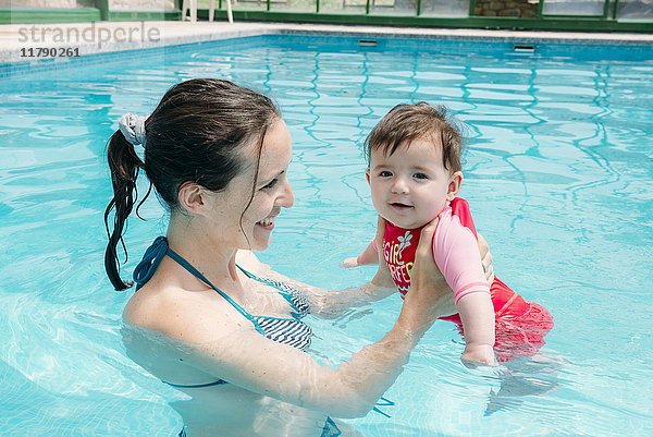 Süßes kleines Mädchen  das mit seiner Mutter im Pool schwimmen lernt.