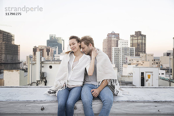 Romantisches Paar sitzt auf der Dachterrasse und genießt die Aussicht.