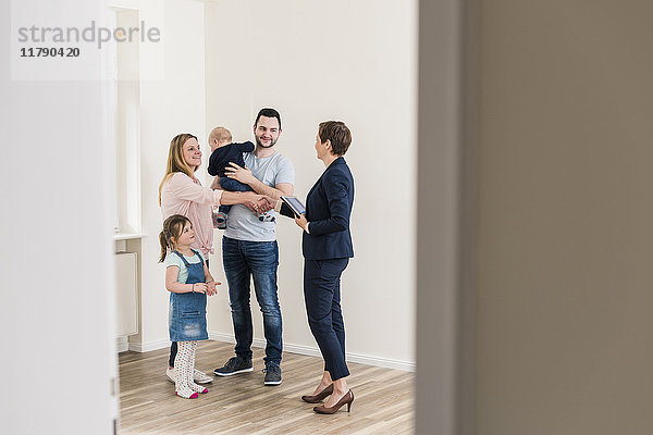 Immobilienmakler und Familie in neuer Wohnung