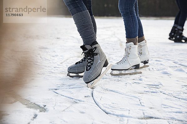 Füße von Schlittschuhläufern auf dem zugefrorenen See