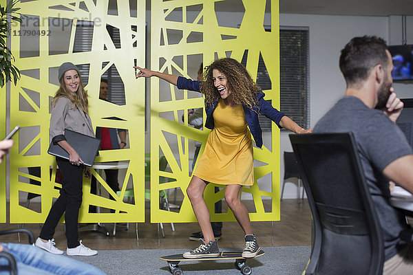 Frau auf dem Skateboard im Büro beim Spaß haben