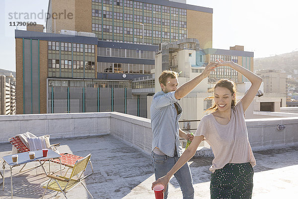 Junges Paar feiert auf einer Dachterrasse  tanzt gemeinsam