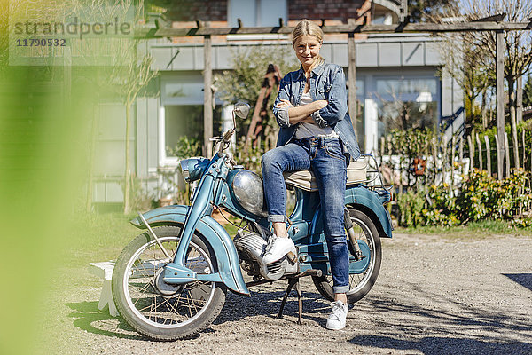 Lächelnde Frau mit Oldtimer-Motorrad