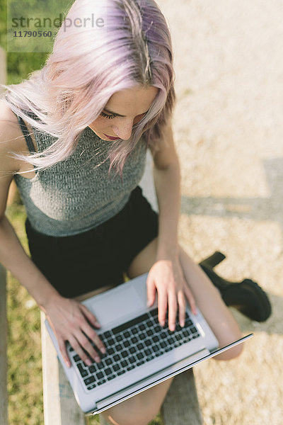 Junge Frau mit rosa grauen Haaren mit Laptop