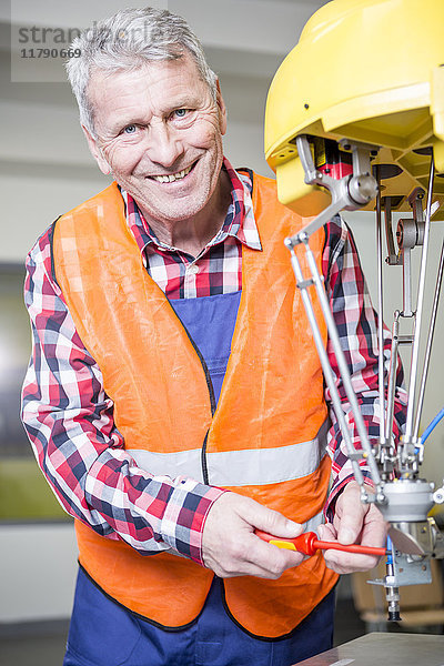 Porträt des lächelnden Technikers beim Einstellen des Industrieroboters