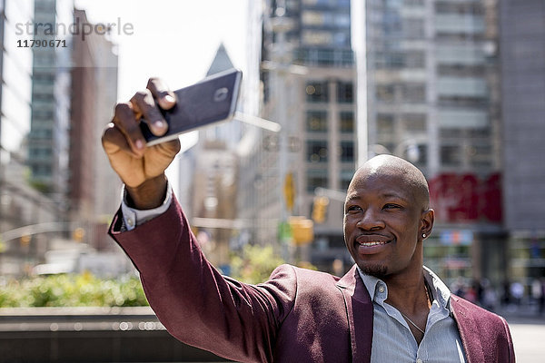 USA  New York City  Manhattan  stilvoller Geschäftsmann  der sich mit seinem Smartphone selbstständig macht.