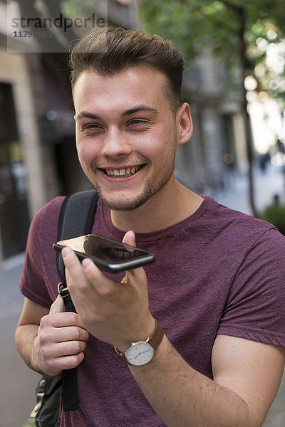 Glücklicher junger Mann mit Handy in der Stadt