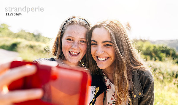 Zwei glückliche Mädchen  die mit einem Selfie nach draußen gehen.