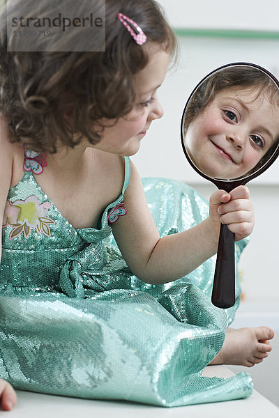 Spiegelbild eines lächelnden kleinen Mädchens mit Blick auf den Handspiegel