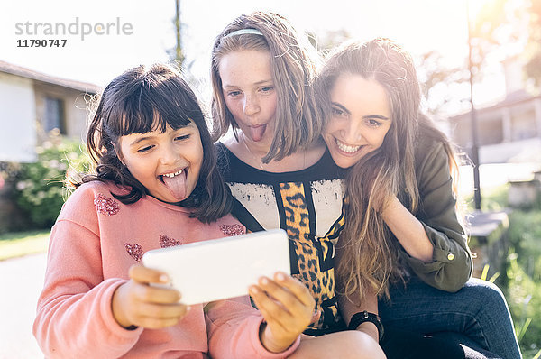Drei verspielte Mädchen mit einem Selfie im Freien
