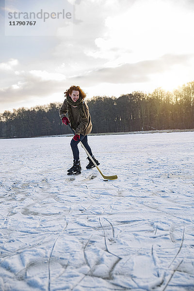 Mann spielt Eishockey auf gefrorenem See