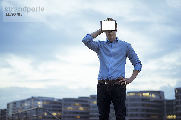 Mann versteckt sein Gesicht hinter Mini-Tablette