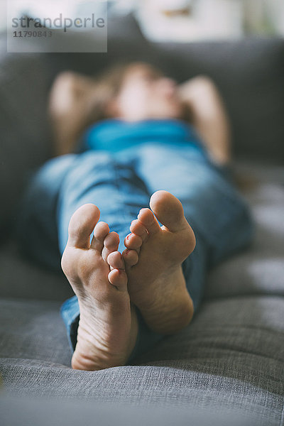 Füße einer entspannten jungen Frau  die zu Hause auf der Couch liegt.