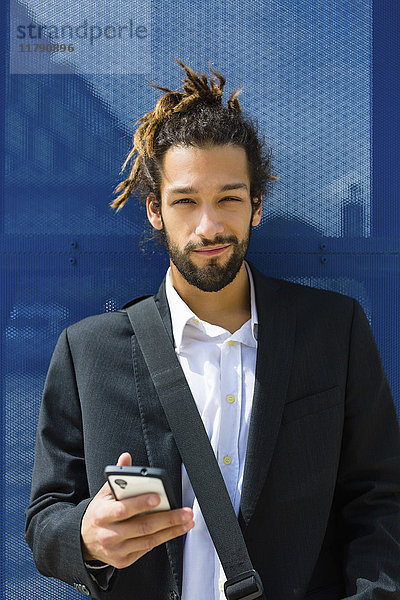 Portrait eines jungen Geschäftsmannes mit Dreadlocks per Smartphone