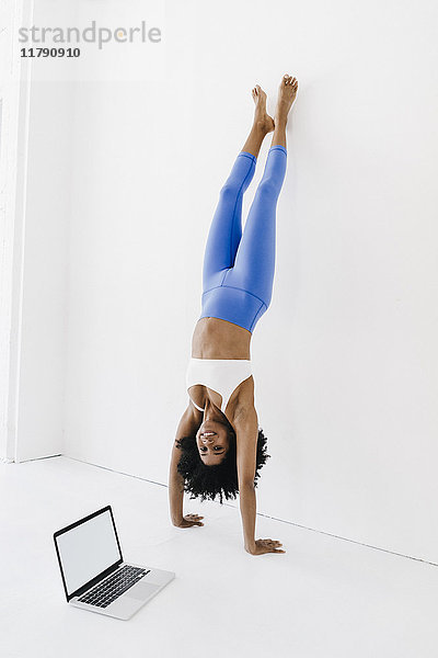 Junge Frau beim Yoga mit Laptop an der Seite