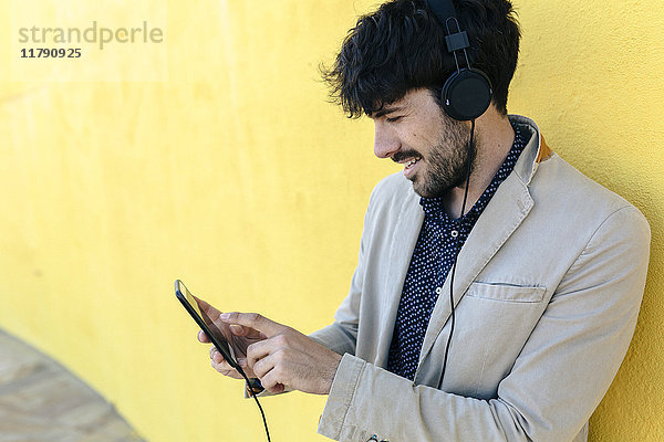 Lächelnder junger Mann mit Kopfhörer und Handy