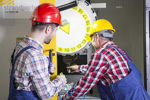 Zwei Männer in der Fabrik arbeiten an der CNC-Maschine