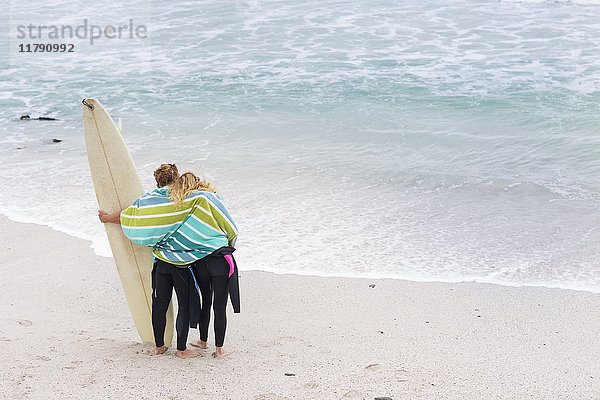 Paar am Strand mit Surfbrett
