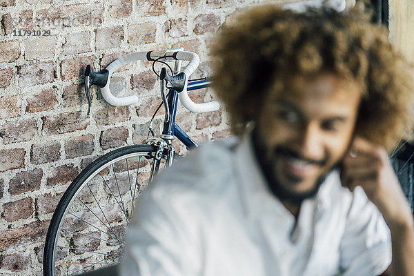 Lächelnder junger Mann mit Fahrrad im Hintergrund