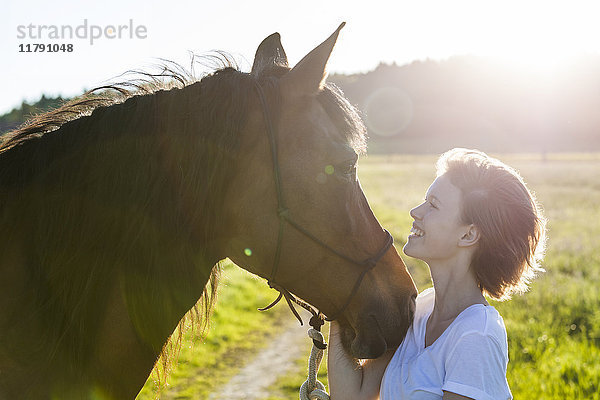 Profile von junger Frau und Pferd im Gegenlicht