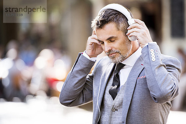 Reife Geschäftsleute mit Kopfhörern in der Stadt