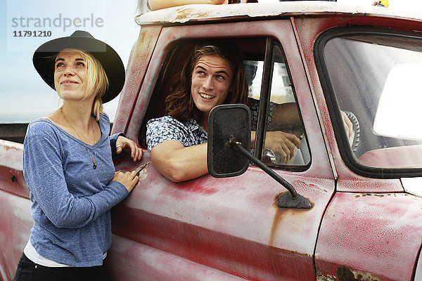 Lächelndes junges Paar mit einem alten Pick-Up