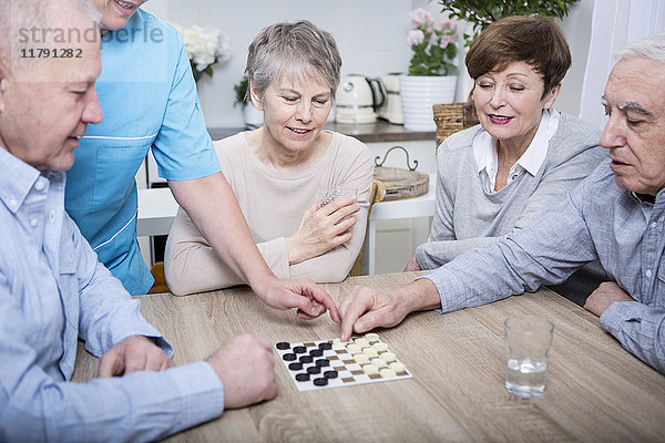 Krankenschwester hilft bei einem Spieleabend für ältere Menschen