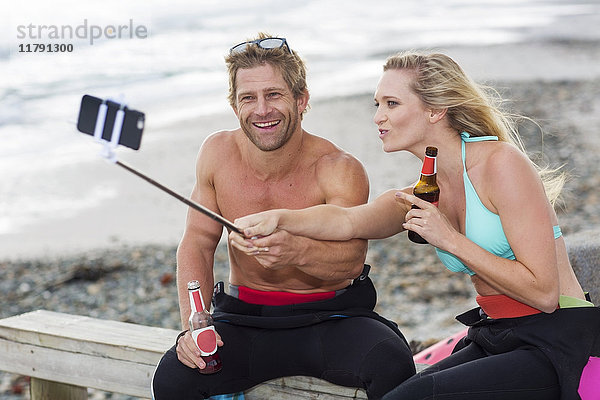 Ein Paar hat Spaß am Strand und nimmt sich einen Selfie.