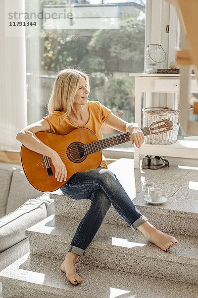 Lächelnde Frau zu Hause mit Gitarre