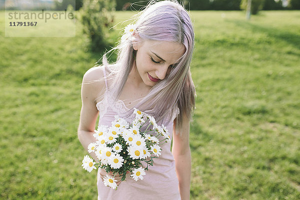 Lächelnde Frau mit Gänseblümchen auf einer Wiese