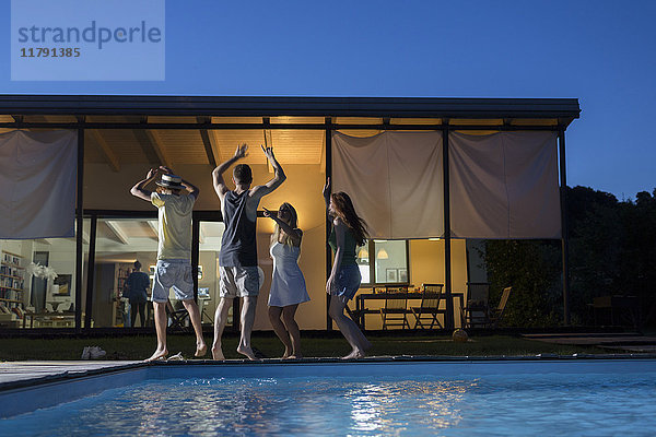 Vier glückliche Freunde beim Tanzen am Pool