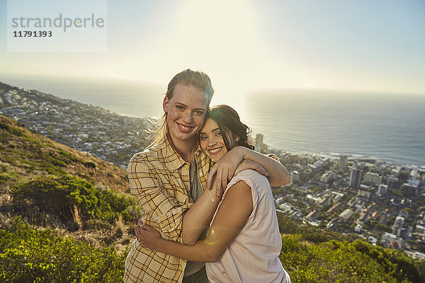 Südafrika  Kapstadt  Signal Hill  Porträt zweier junger Frauen  die sich über der Stadt umarmen