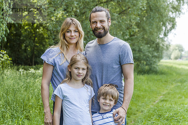 Porträt einer glücklichen Familie auf einer Wiese stehend
