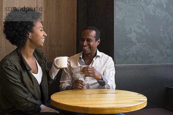 Vater und erwachsene Tochter sitzen in einem Café und haben Spaß.